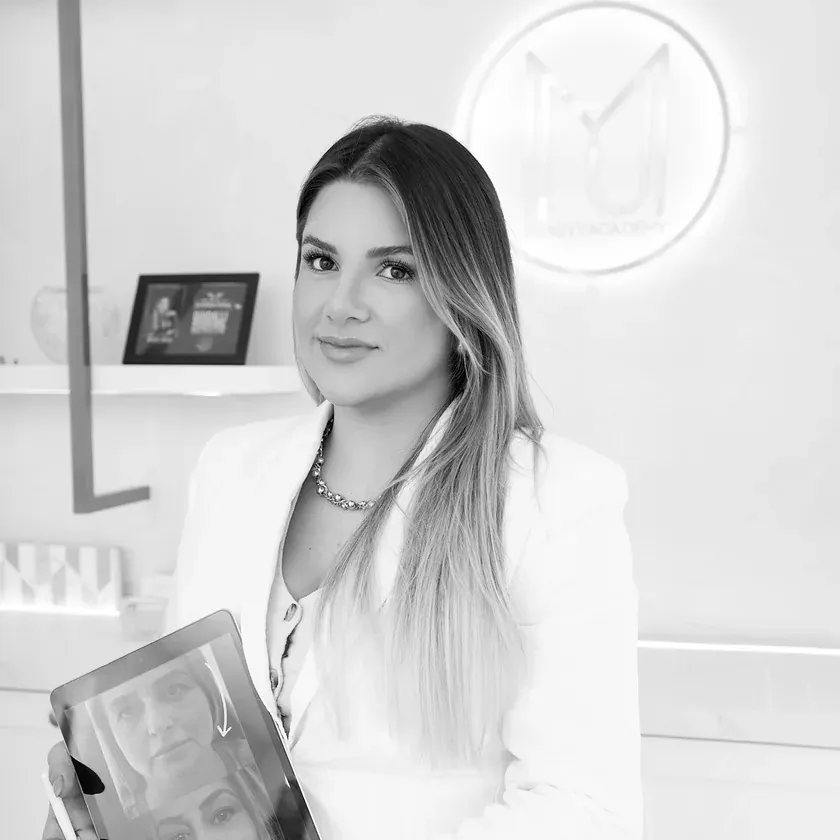 Dra. Manu Maia com um tablet na sala de atendimento, em preto e branco