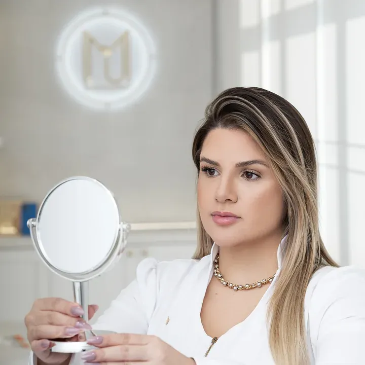 Dra. Manu Maia com espelho de mão durante uma avaliação
